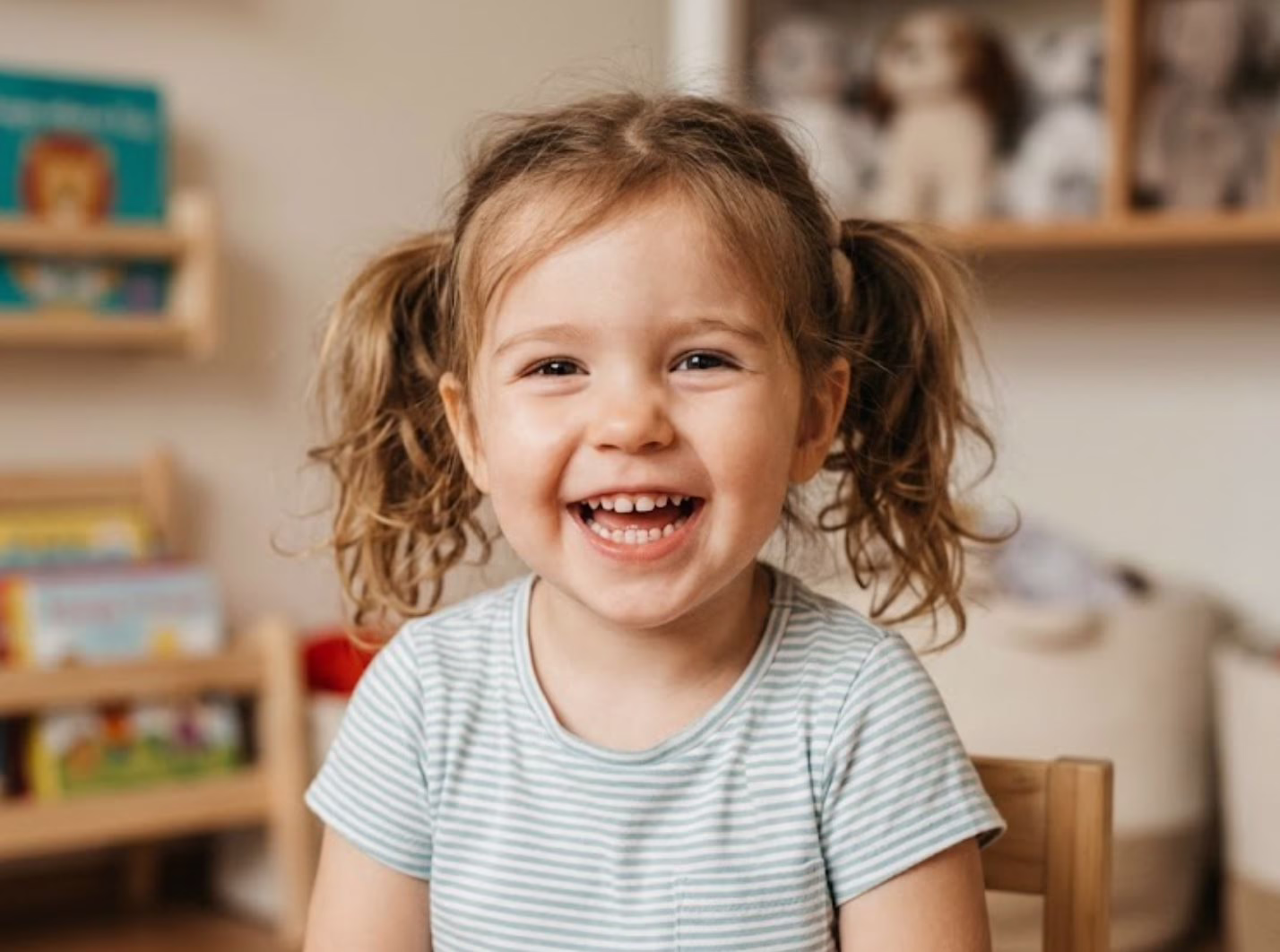 A happy shild with pigtails smiling brightly in a child friendly dental environment showing healthy jaw development and a wide smile.
