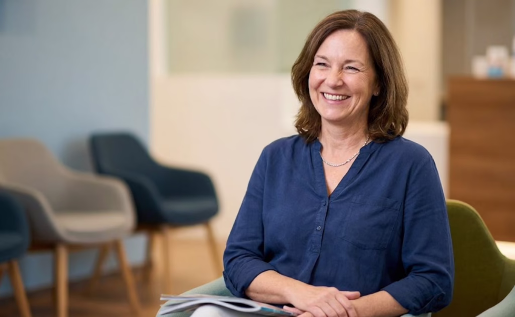 A smiling woman sitting in a modern, comfortable dental office waiting area, reflecting a calm and welcoming environment at Central Park Dental and Orthodontics in Mansfield.